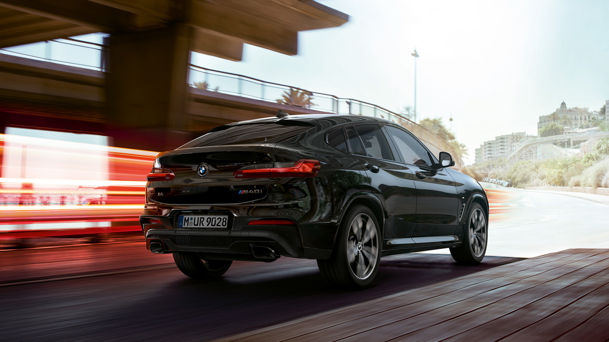 BMW X4 M40i, set forfra let drejet. BMW X4 M40i i safirsort metallic, kørende, eksteriør, set forfra let drejet med lysstriber.
