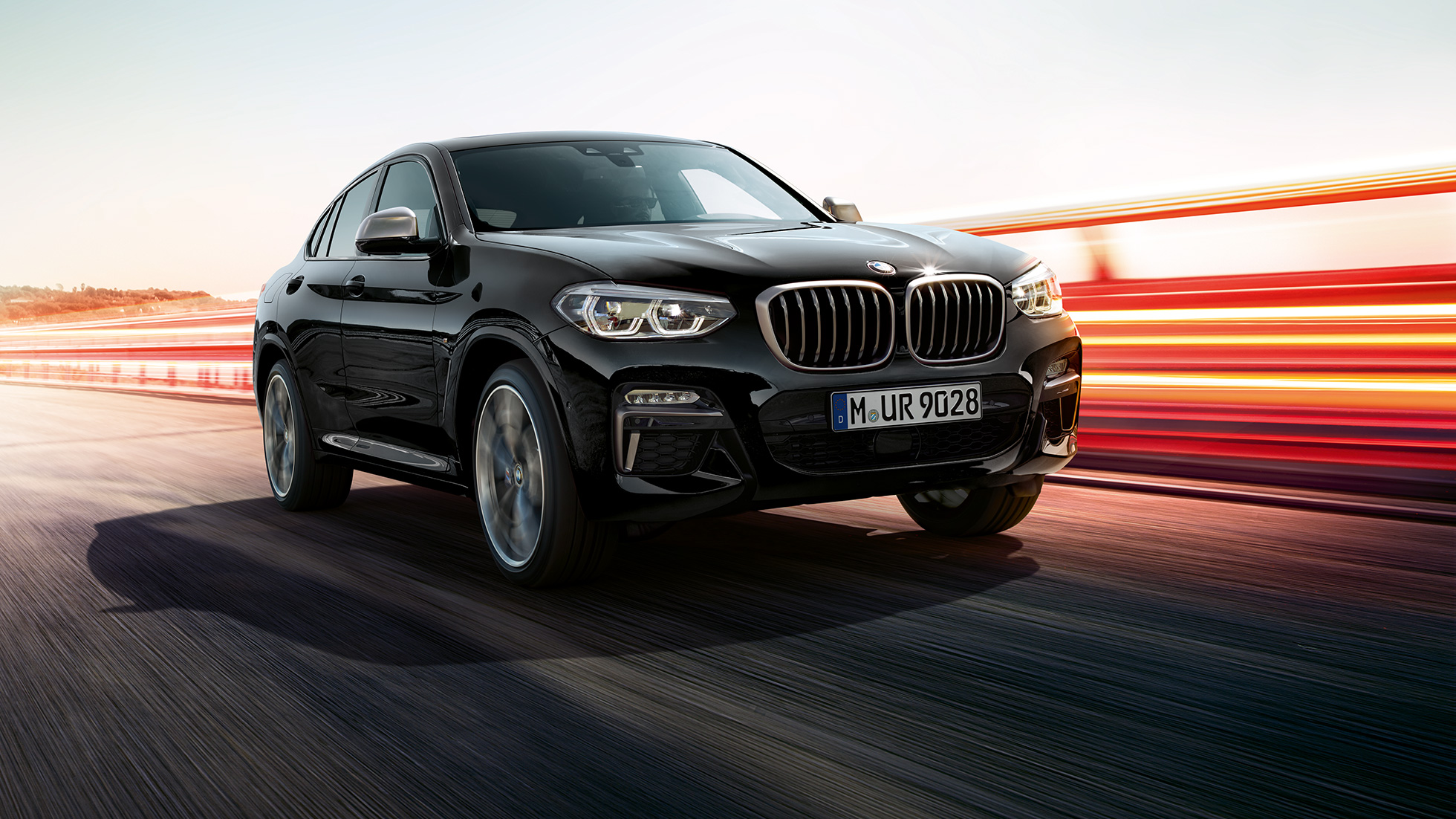 BMW X4 M40i og BMW X4 M40d, set forfra let drejet. BMW X4 M40i i og BMW X4 M40d i safirsort metallic, eksteriør, set forfra fra venstre, let drejet med lysstriber.