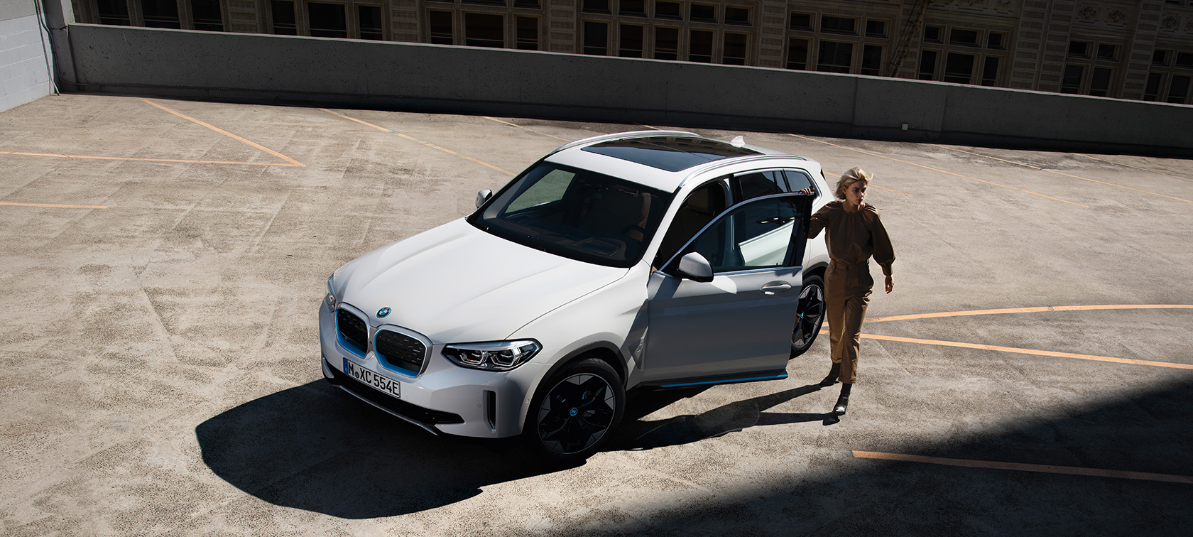 BMW iX3 G08 set forfra let drejet med en kvinde BMW iX3 G08 2020 Mineral White metallic set forfra let drejet med en kvinde i urbane omgivelser