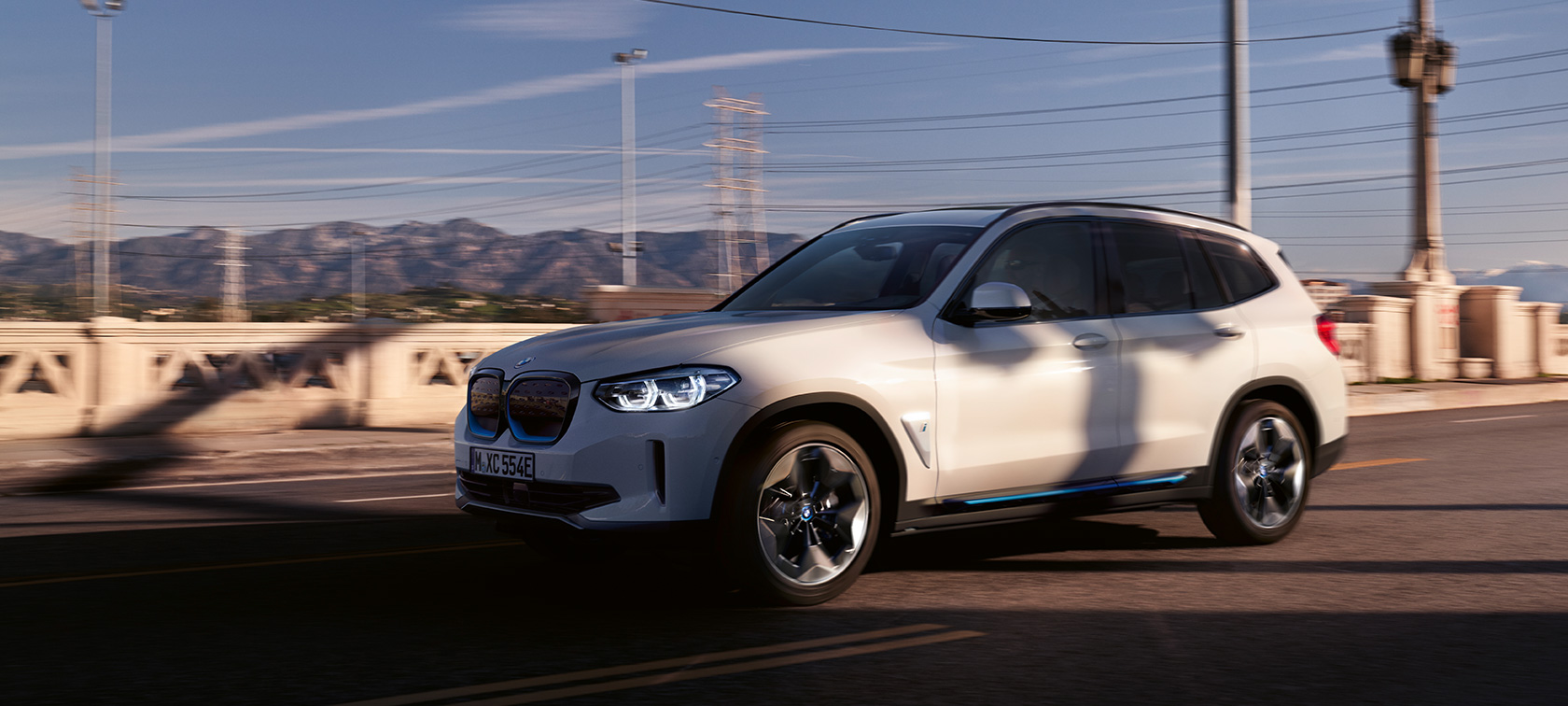 BMW iX3 G08 set forfra let drejet kørende på en vej BMW iX3 G08 2020 Mineral White metallic set forfra let drejet kørende på en vej
