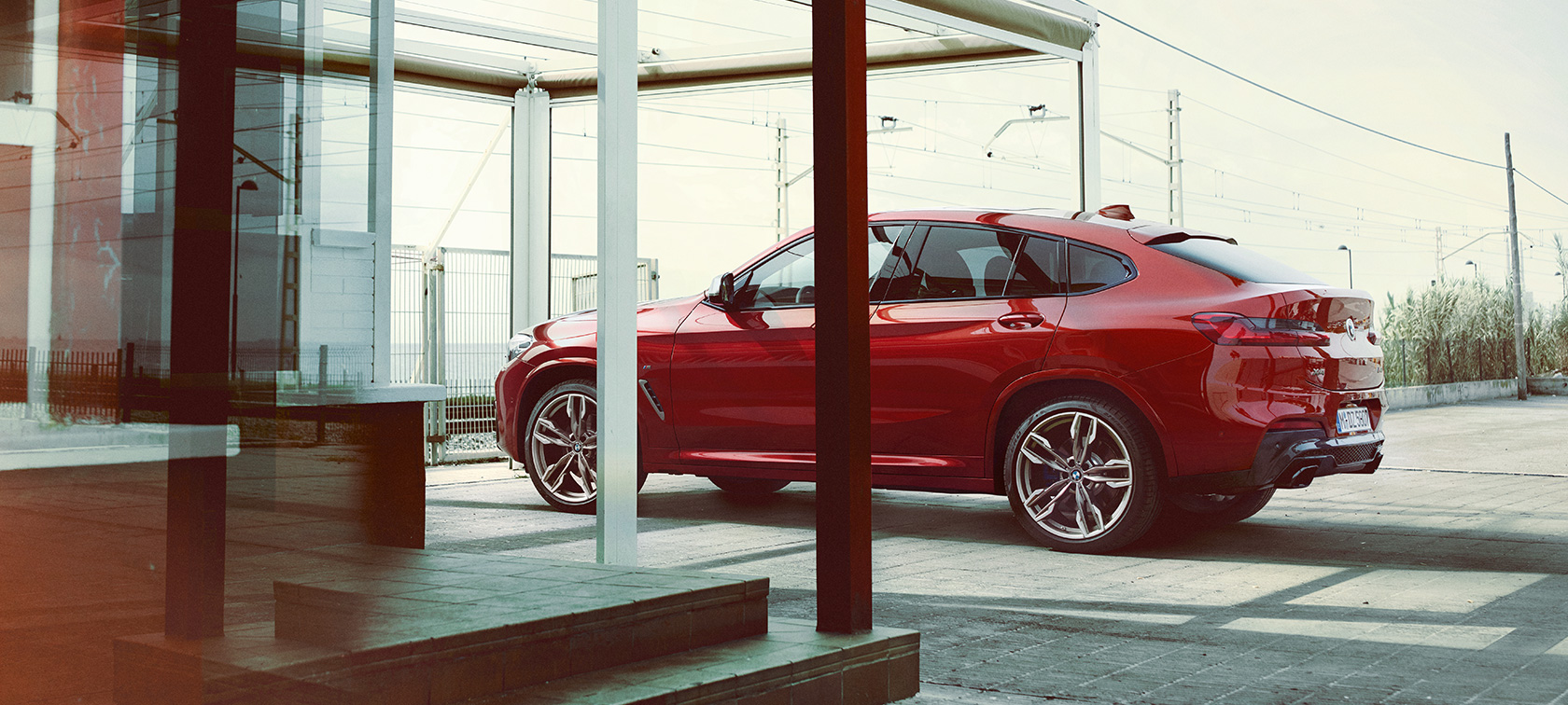 BMW X4 set fra siden BMW X4 M40i G02 2018 Flamenco Red Brillant-effekt set fra siden parkeret