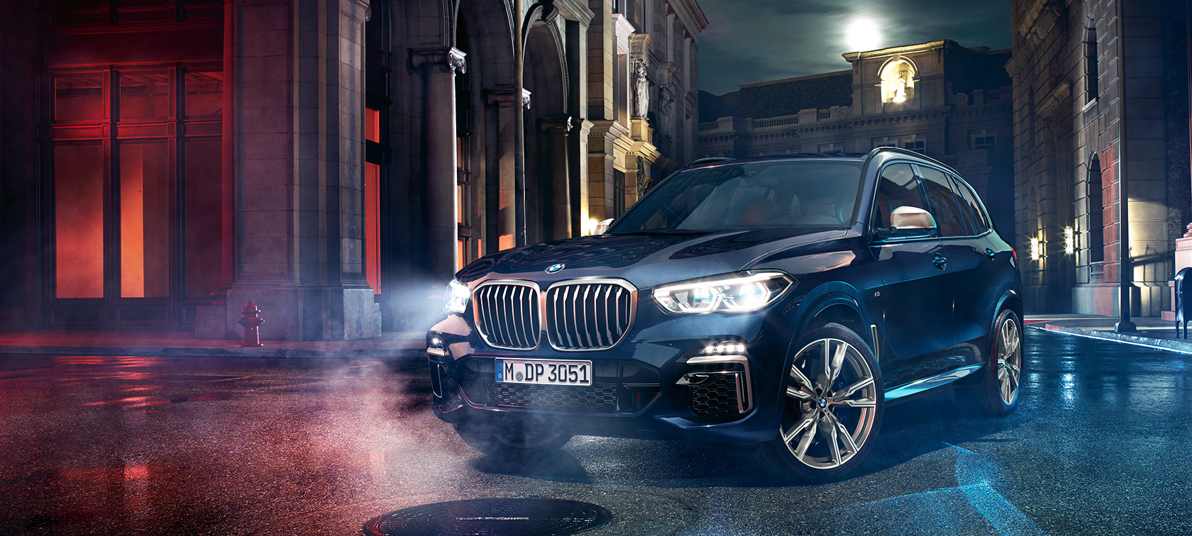 BMW X5 M50d på farten BMW X5 M50d på vejen om natten med storbyen som baggrund