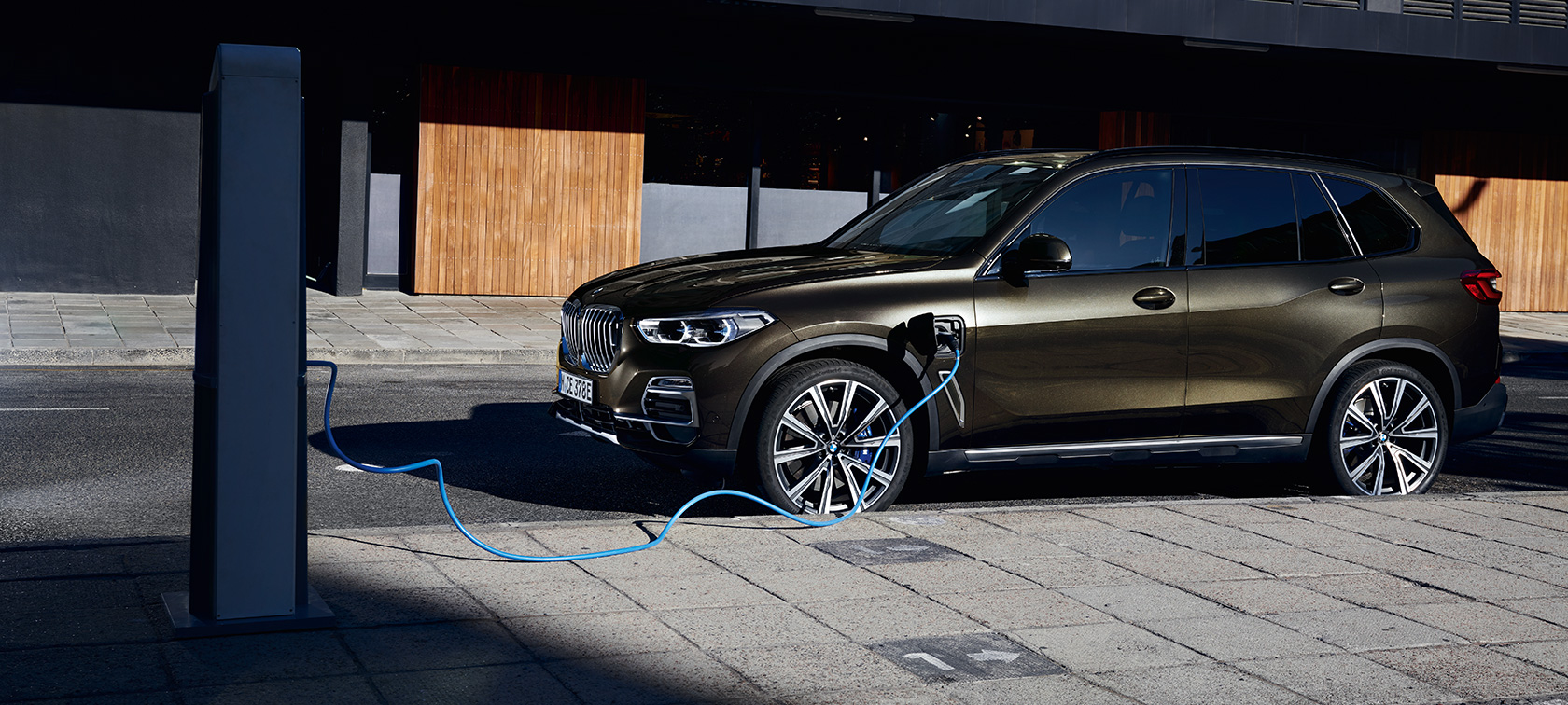 Plug-in-hybrid BMW X5 xDrive45e G05 set fra siden let drejet Plug-in-hybrid BMW X5 xDrive45e G05 set fra siden let drejet under opladning