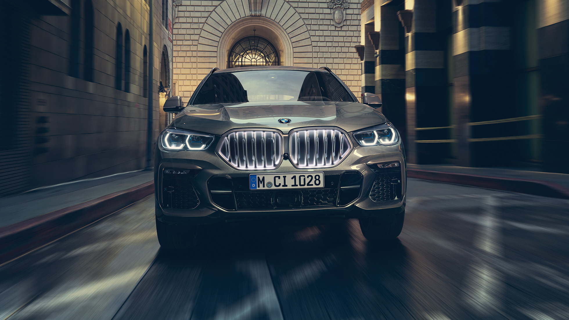 BMW X6 med BMW nyre ‘Iconic Glow’. BMW X6 set forfra foran et urbant miljø.