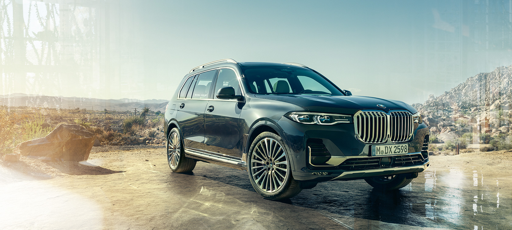 BMW X7, set forfra let drejet fra venstre BMW X7 i Arctic Grey stående stille med en ørken i baggrunden, set forfra let drejet fra venstre, G07 2019