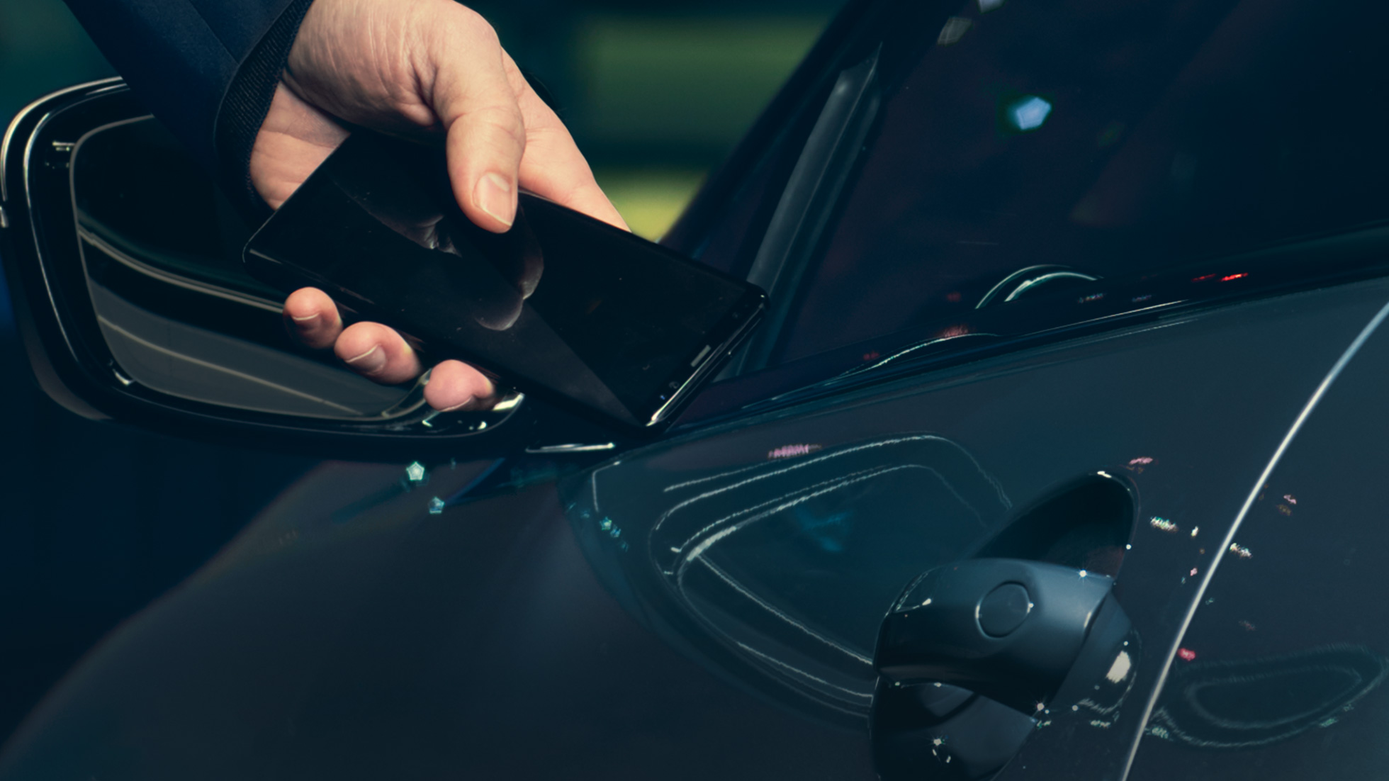 Digital Key Digital Key: Mand står uden for sin bil og holder smartphonen til bilens dør