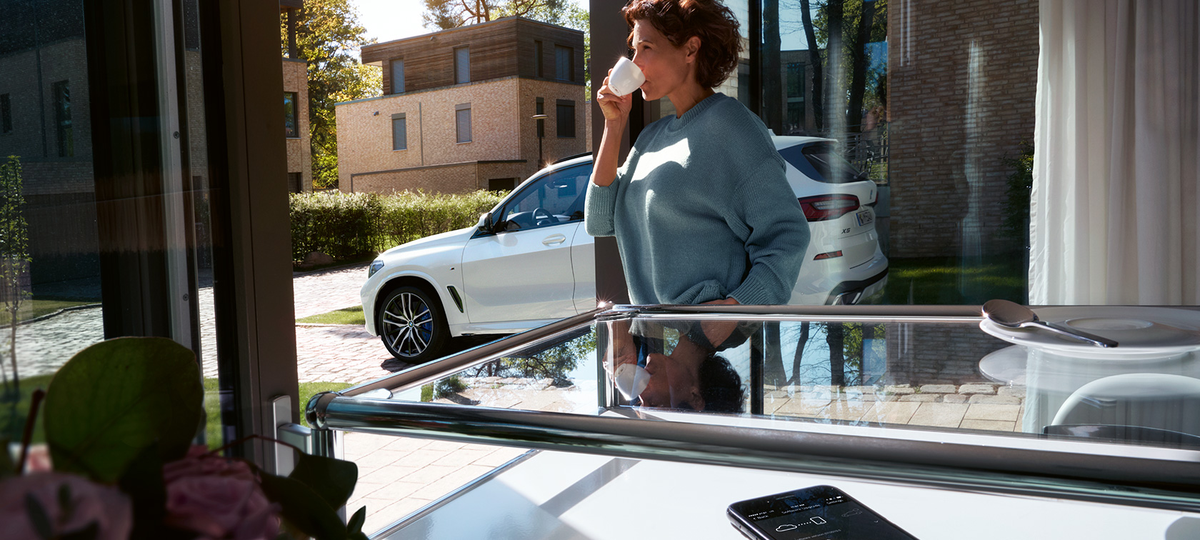 BMW Remote Software Upgrade En kvinde drikker af en kop, mens BMW Remote Software Upgrade opdaterer bilsoftwaren i hendes BMW X5