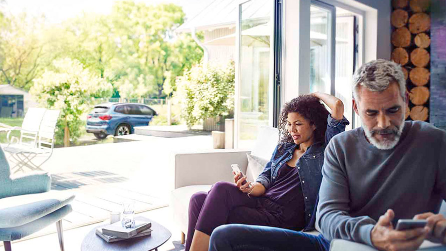 Remote Services Mand og kvinde sidder i sofa og bruger Remote Services på deres smartphones