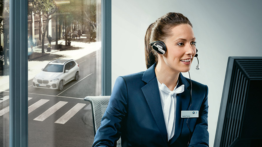 Concierge Service Concierge Services: BMW medarbejder med headset på sidder foran skærm