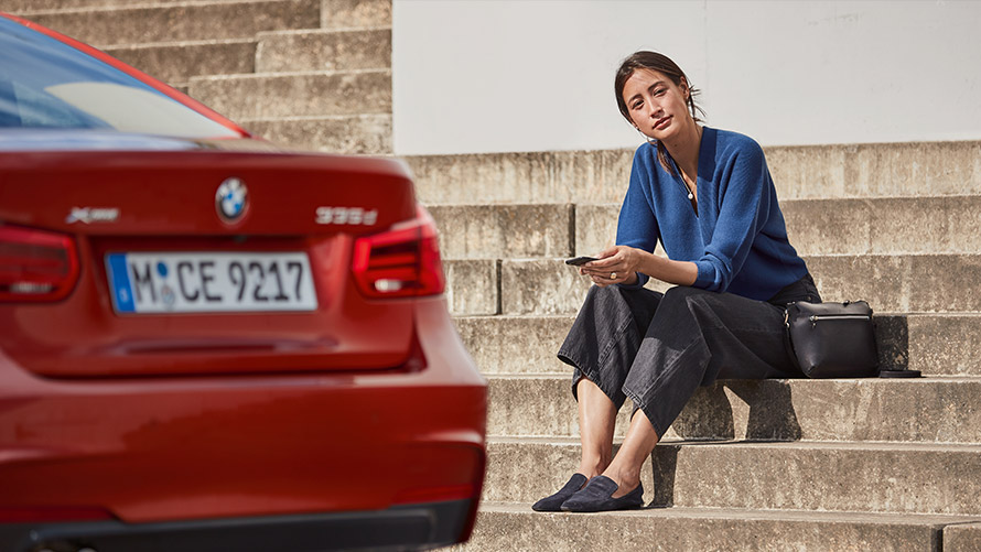 Service & Vejhjælp Kvinde sidder foran sin røde BMW og bruger Service & Vejhjælp