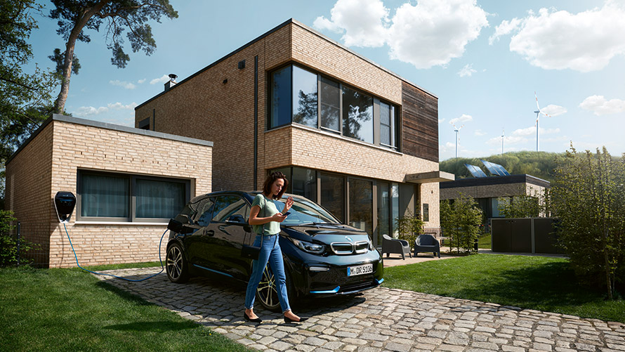 Digital Charging Service Kvinde går ude foran sin BMW i3 og bruger Digital Charging Service via sin smartphone
