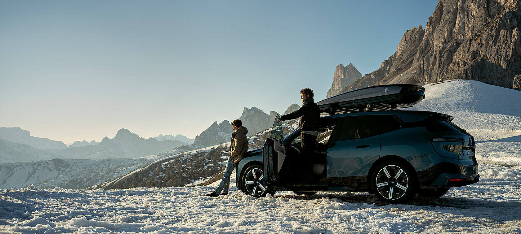BMW Originaltilbehør og BMW Service til efterår og vinter En gruppe mænd med en BMW iX i et snelandskab
