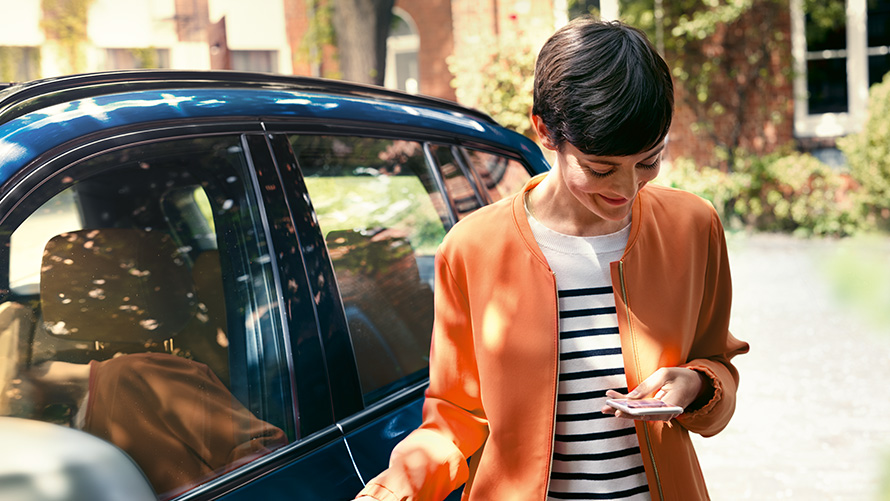 BMW sommertilbud BMW Teleservices BMW sommertilbud BMW Teleservices en kvinde står foran en BMW og benytter en smartphone