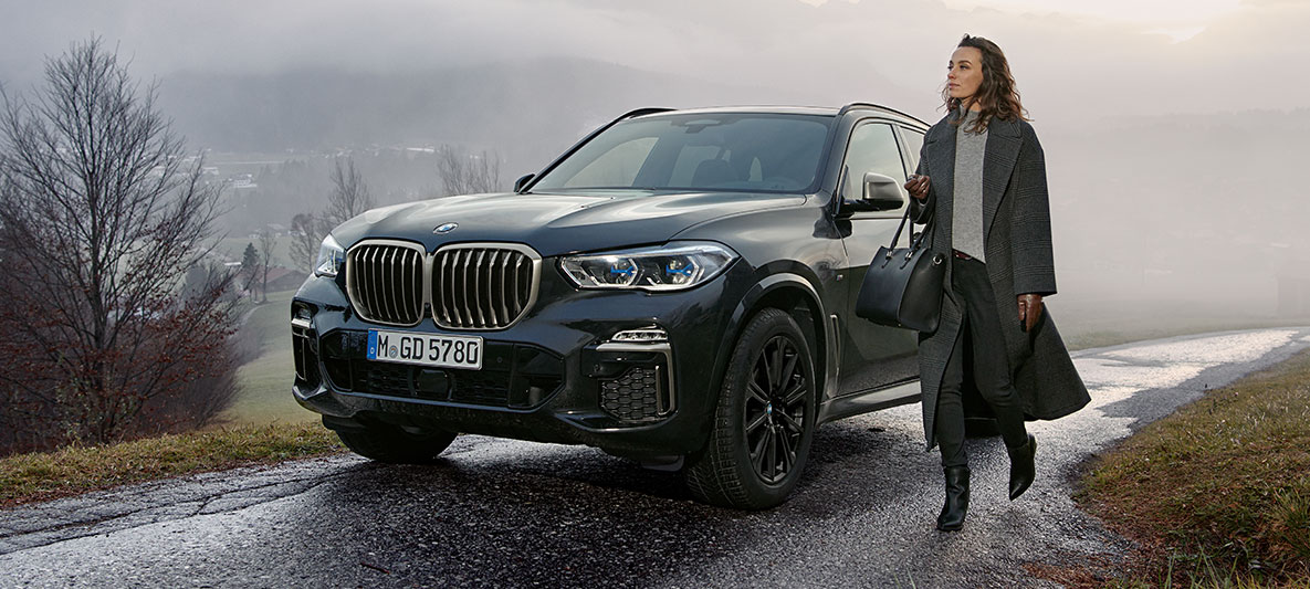 Mand med solbriller foran blå BMW Mand med solbriller foran blå BMW