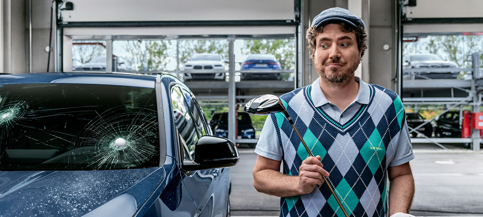 Mand, som holder en golfkølle ved siden af en BMW, der er blevet ramt af en golfbold i frontruden. Mand, som holder en golfkølle ved siden af en BMW, der er blevet ramt af en golfbold i frontruden.