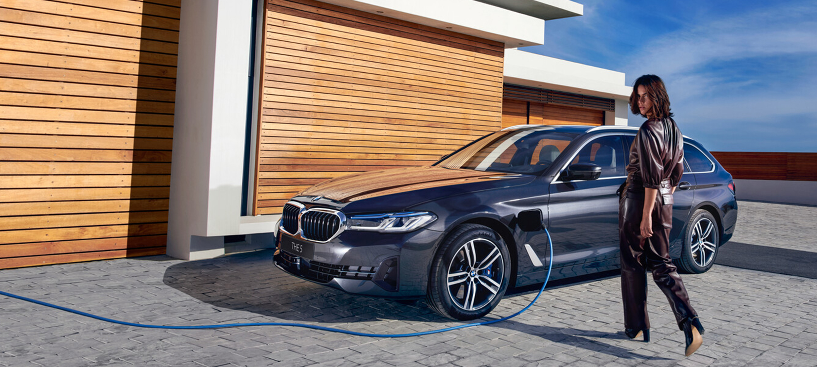 BMW 5-serie Touring G31 Facelift 2020 Sophisto Grey 7/8 frontvisning kørende i udkanten af en by