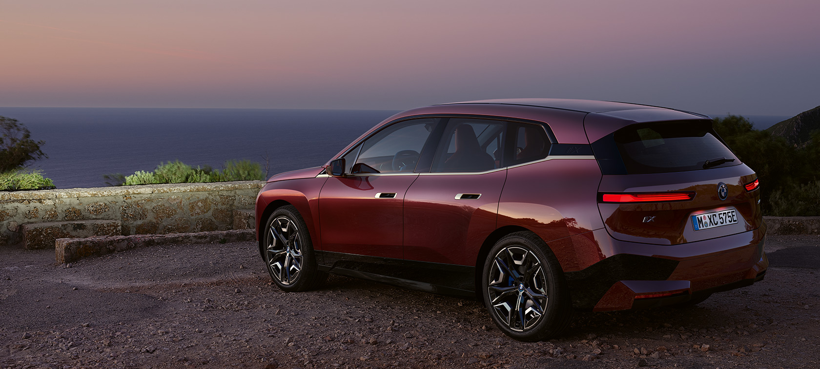 BMW iX i20 2021 elektrisk SUV BMW iX xDrive50 Aventurin Red foran en kyst