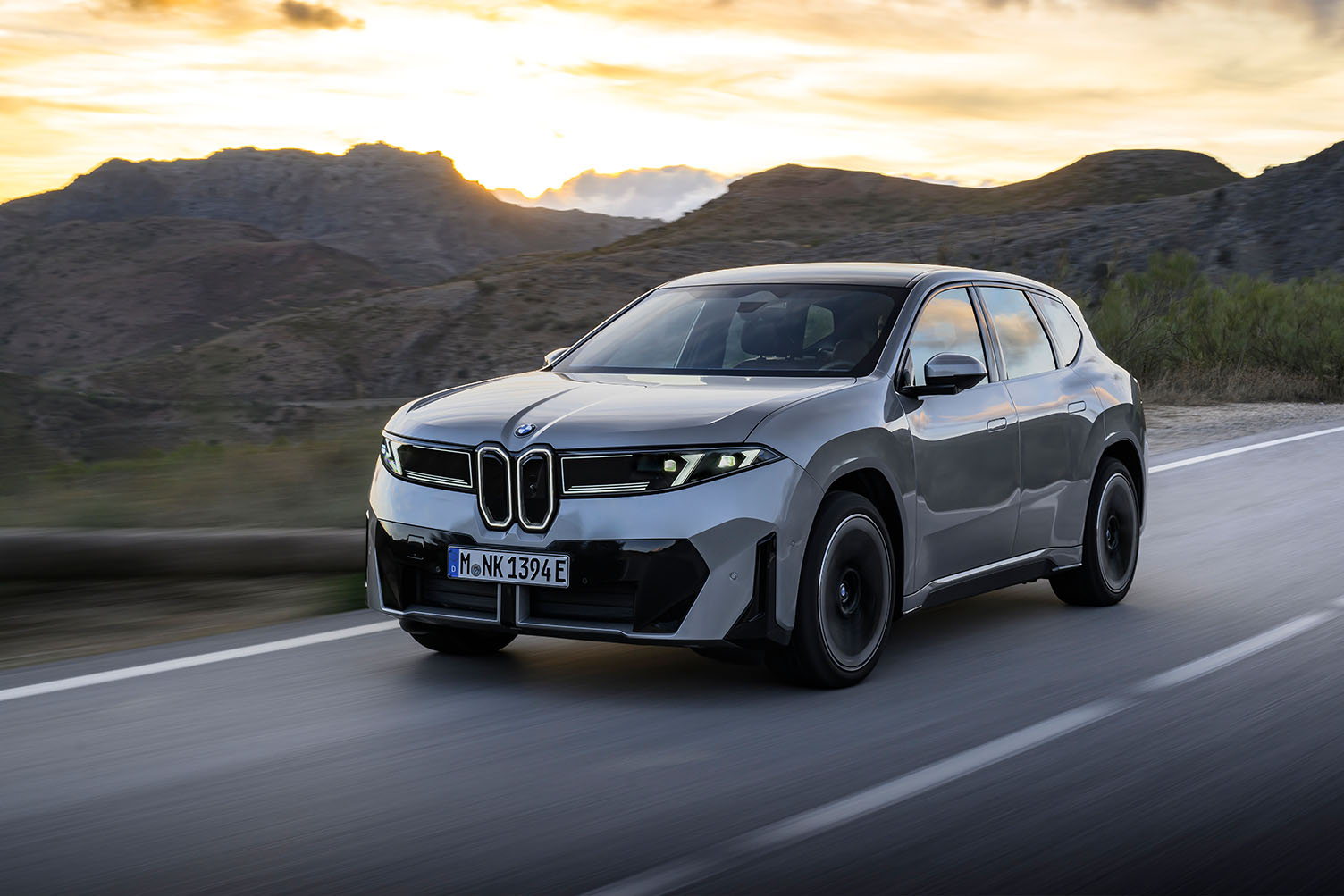 Grå BMW iX3 set skråt forfra i solnedgang