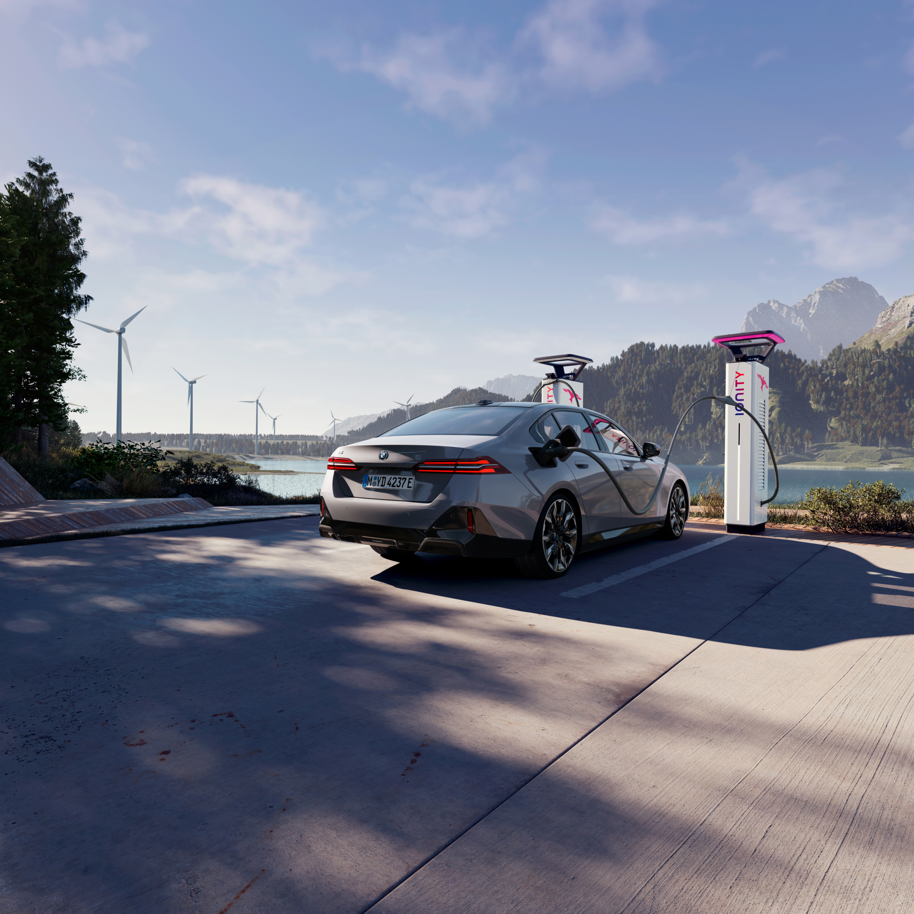 BMW lader ved en ladestation med udsigt over vand, bjerge og vindmøller