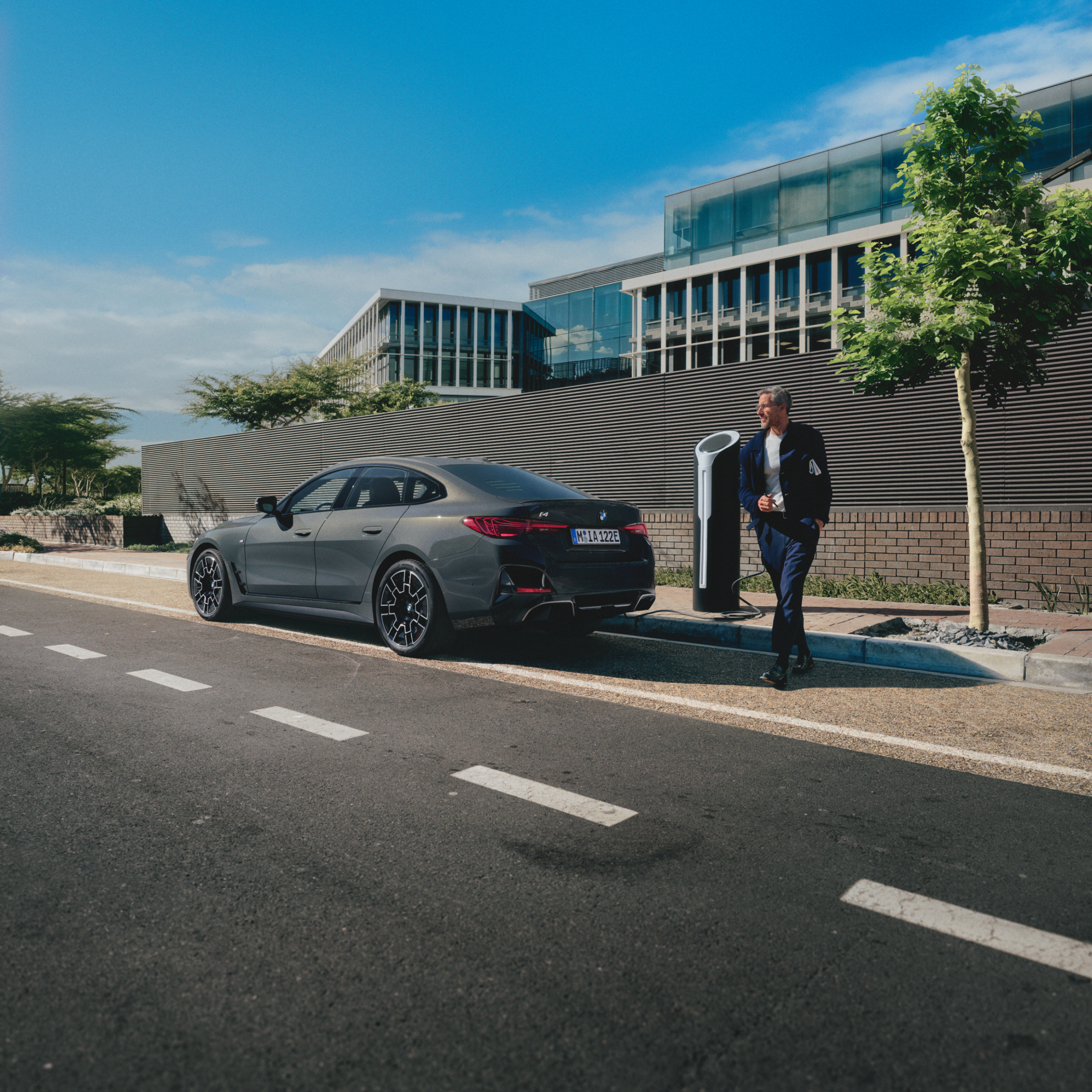 Person, der står bag en BMW, der er ved at oplade ved en vejside
