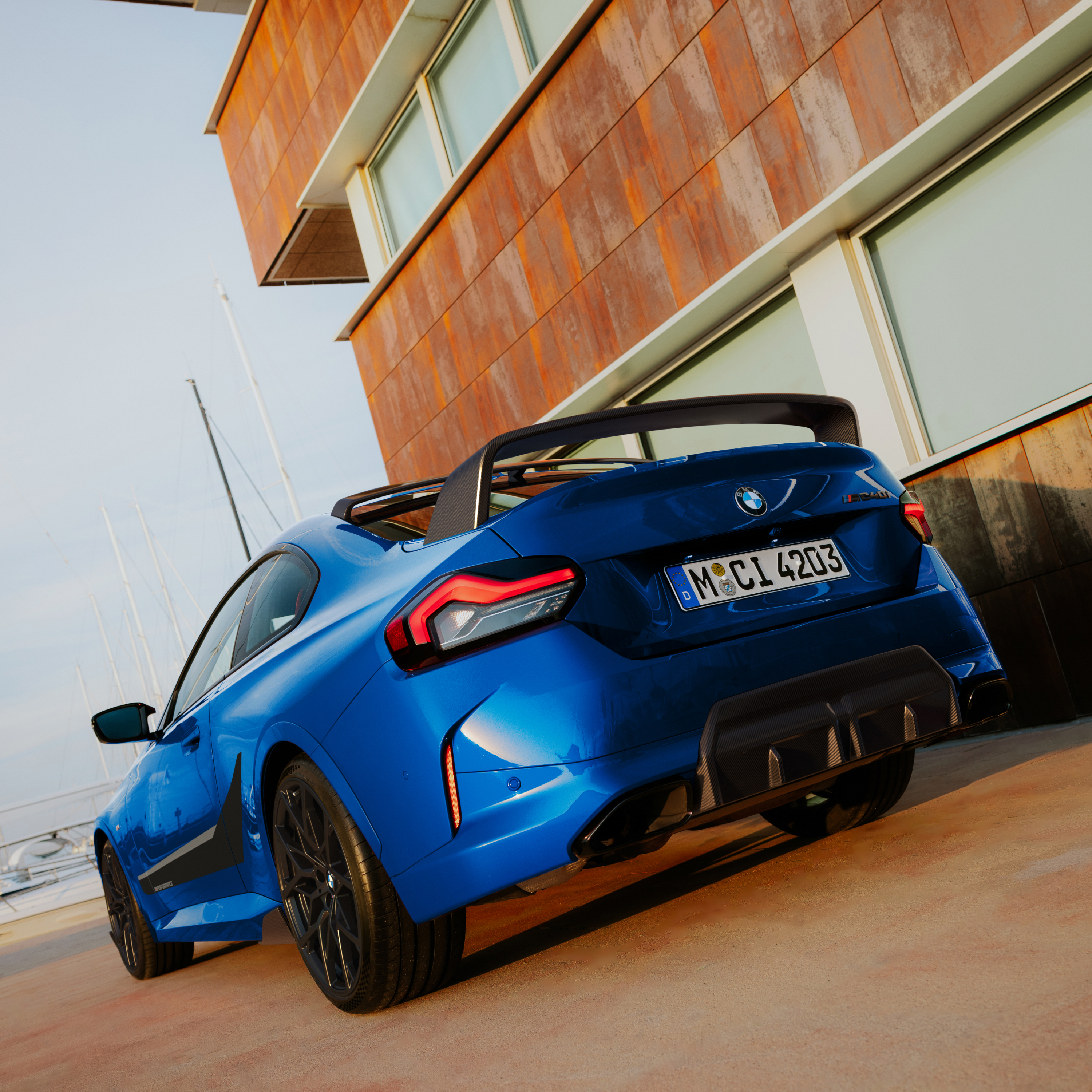 BMW med M Performance hækspoiler parkeret foran et hus