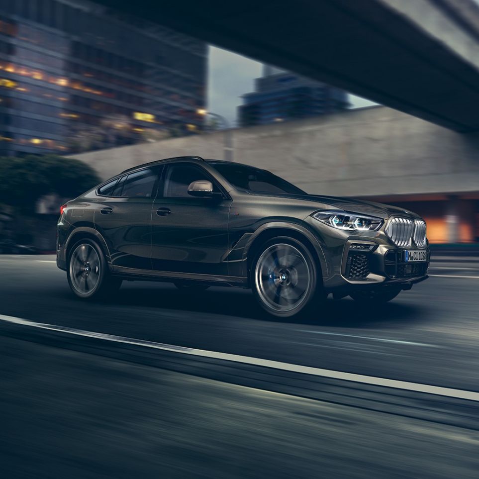 BMW X6 driving. BMW X6 set forfra let drejet kørende foran et urbant miljø.